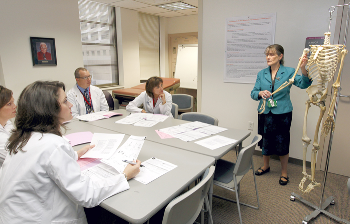 Dr. Karen Szauter, professor of gastroenterology and senior medical educator, demonstrates the movement of the shoulder during Project Medical Education, a daylong program to introduce people to medical school