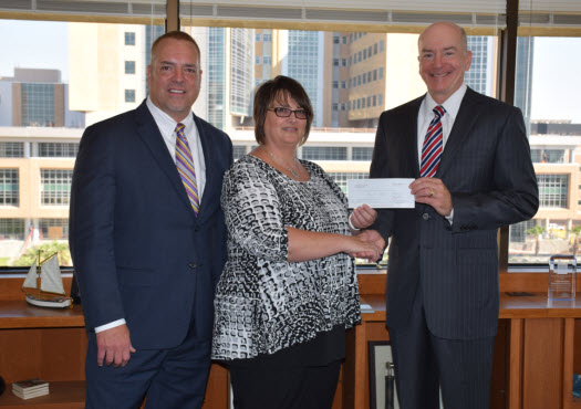 Paul Schultz, vice president of Hospitality for Landry’s, Inc., and Michelle Beckwith, area director of Catering for the San Luis Resort, present a check to Dr. David Callender.