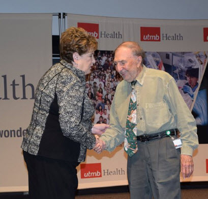 Dr. Leonard Swischuk shakes hands with Donna Sollenberger. 