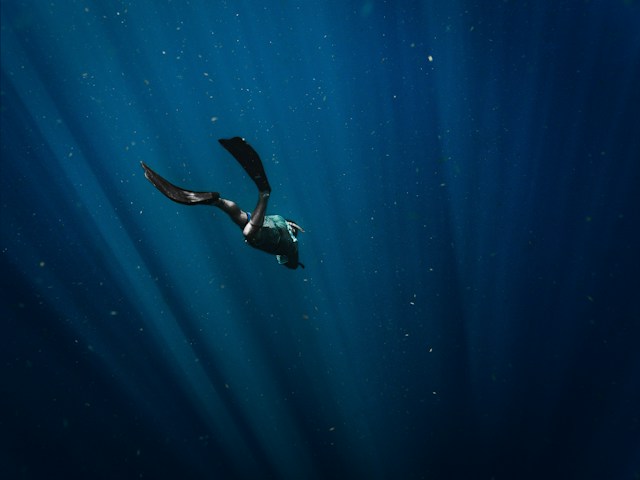 A diver in scuba gear descending into the abyss
