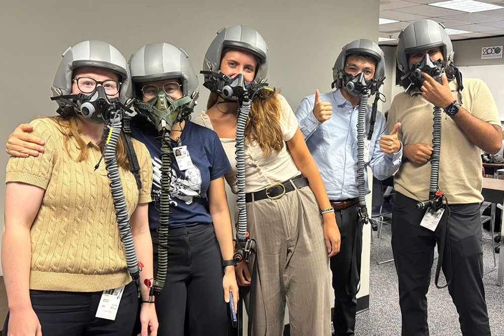 Group of men and women wearing aviator oxygen masks connected to flight helmets 