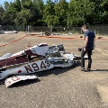 Person examines the wreckage of a small airplane at an outdoor crash-investigation site.