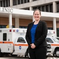 Woman standing outside a clinic entrance beside an ambulance.