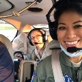 Two people wearing aviation headsets sit inside a small airplane.