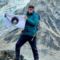 Person holds an Aerospace Medicine flag in front of snow-covered Himalayan mountains.