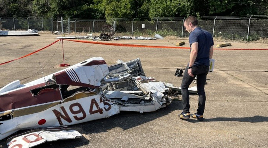 An UTMB Aerospace & Exploration Medicine resident standing near wreckage of small general aviation aircraft.