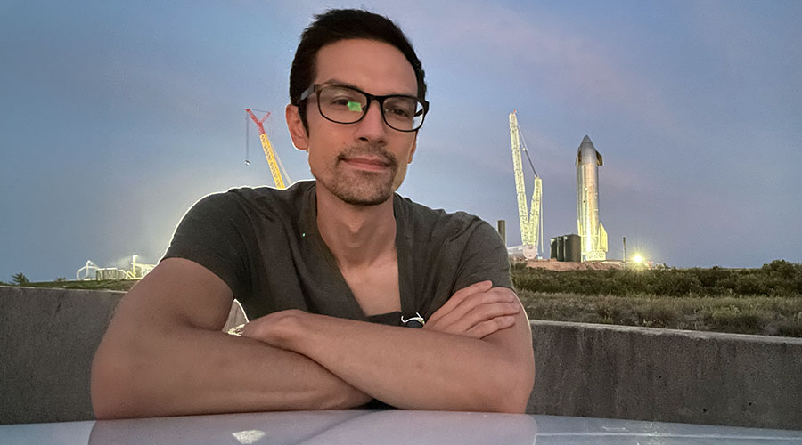 Man in foreground with SpaceX Starship rocket in background.