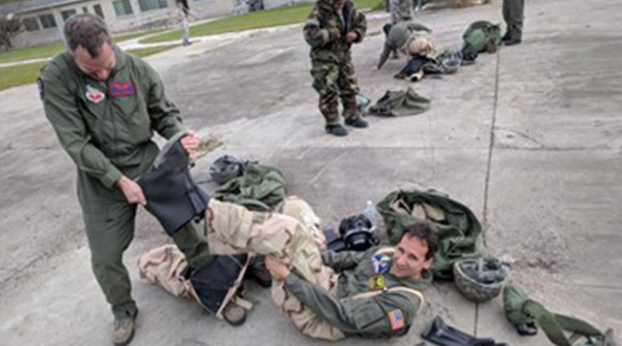 UTMB Aerospace Medicine resident lying on the ground and another rapidly trying to take the other’s boots off during military training scenario.