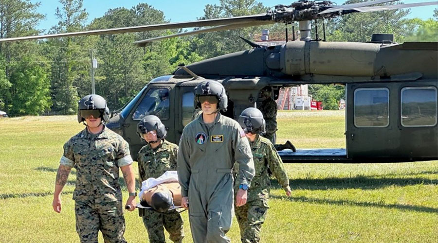 UTMB Aerospace & Exploration Medicine resident and US Army personnel carrying a simulated patient off a helicopter on a stretcher.