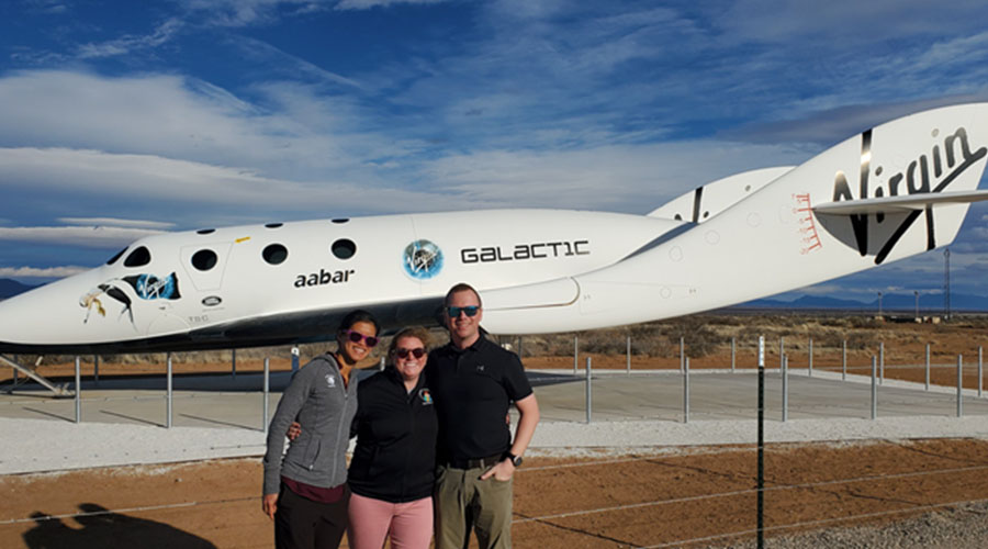 Three UTMB Aerospace & Exploration Medicine residents in front of Virgin Galactic spaceship static display during a commercial spaceflight rotation.