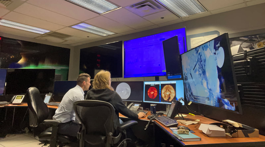 ASM Resident at UTMB sitting console with a radiation specialist at the Space Radiation and Analysis Group console position at Mission Control at NASA to real-time monitor space radiation during an EVA.