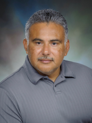 Studio portrait of a UTMB Medicine Services grants team staff member wearing a gray collared shirt against a neutral background.