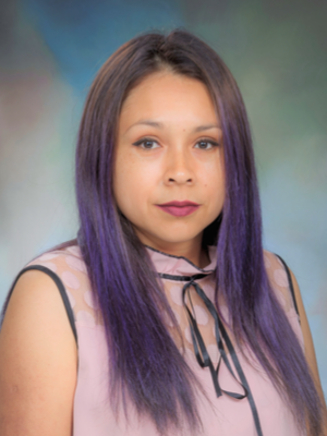 Studio portrait of a UTMB Medicine Services grants team staff member wearing a light-colored sleeveless blouse with a tie detail, against a neutral backdrop.