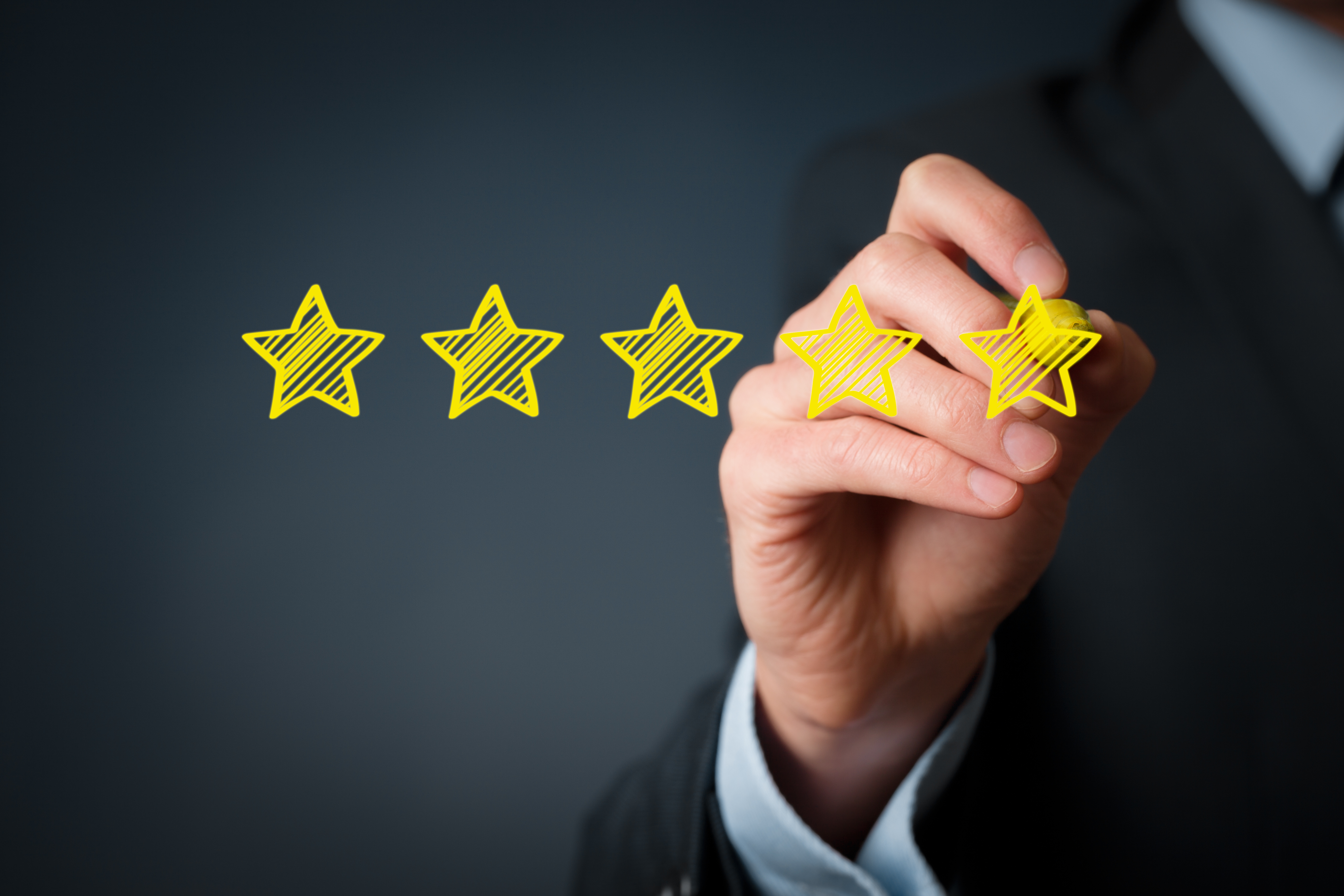 A hand holding a marker completes a five-star rating graphic, representing quality evaluation and performance excellence.