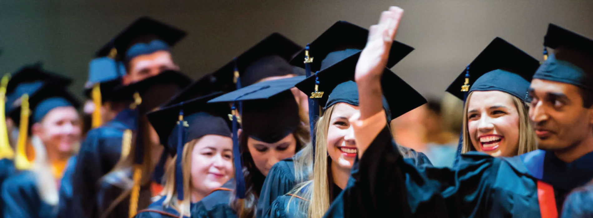 graduating students smiling and waving