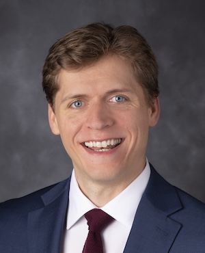 man wearing a suit smiling in a studio portrait setting