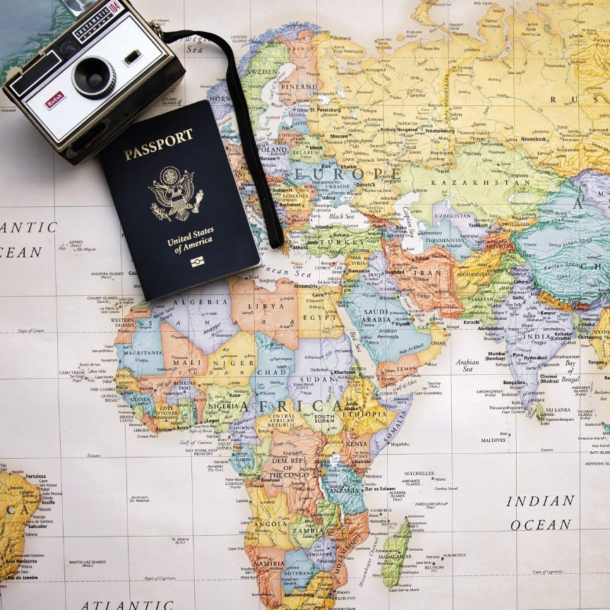 A United States passport and vintage camera resting on a world map, symbolizing international travel, global education, and cross-cultural experiences.