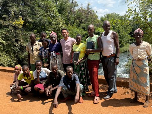 People posing on a bridge over a flowing river in Kenya