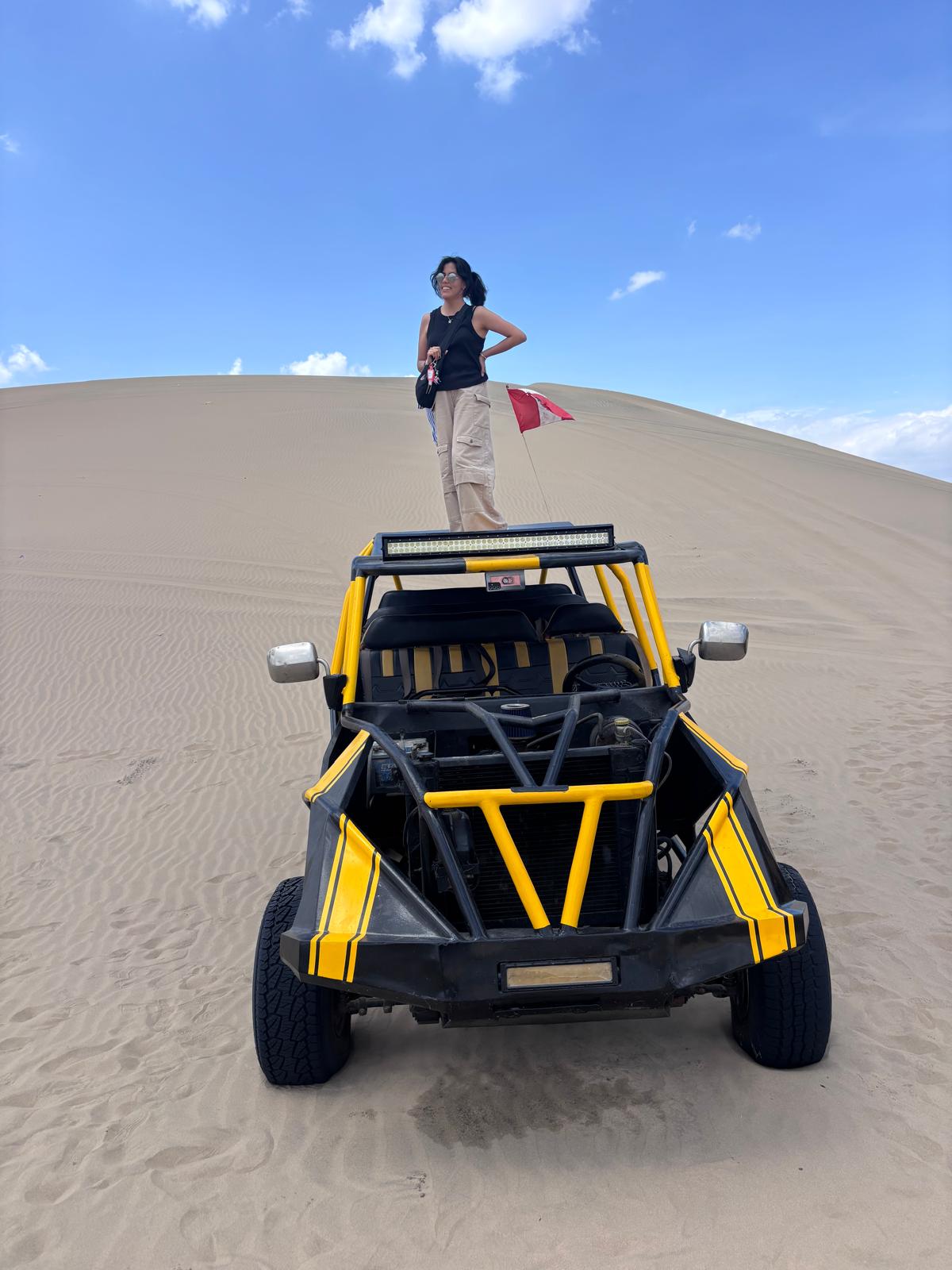 female posing for a photo on top of a buggy car in the desert