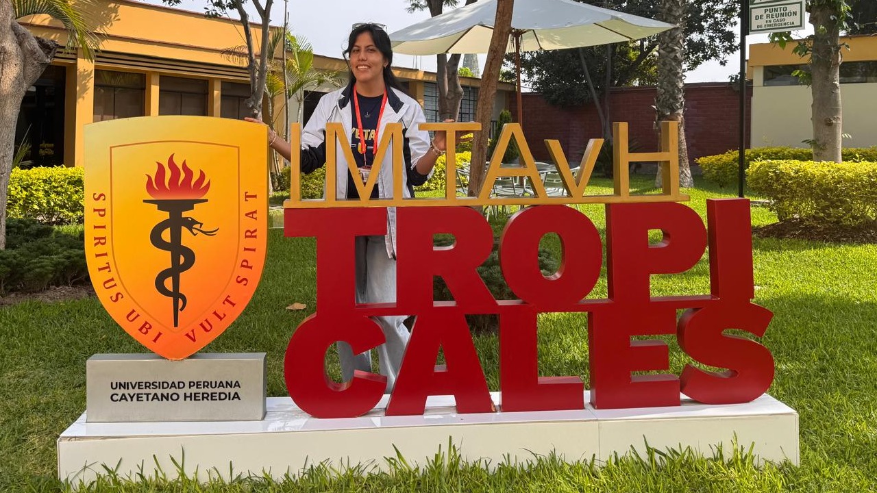 female student standing behind a university logo sign