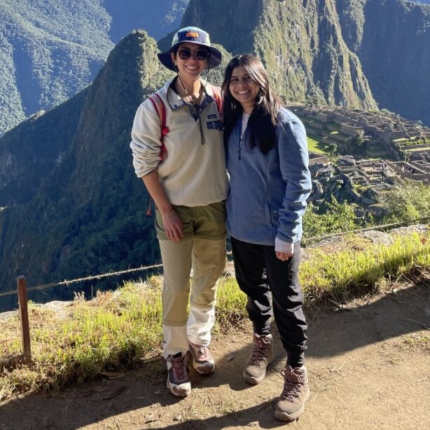 Two people standing on dirt road in front of mountain in Peru