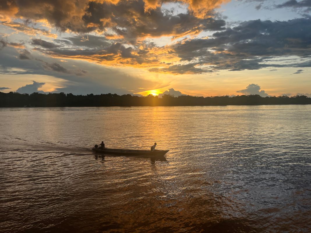 Two people kayaking in wide river during sunset.