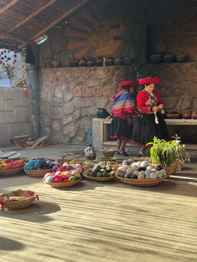Fowler_4 Two women in traditional Peruvian clothing demonstrating yarn dyeing surrounded by baskets of colorful wool