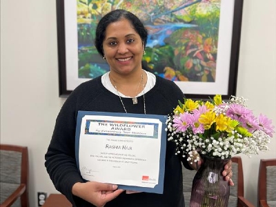 Nurse holding flowers and award