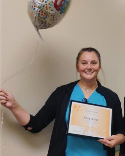 Photo of woman holding balloons and award