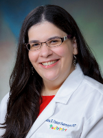 Selfie of woman in purple hat and shirt on a hike