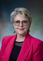 Professional headshot of Dr. Susan Chubinskaya. Light complected woman with short, ash-blonde hair, glasses, a black shirt, and a fuchsia blazer.