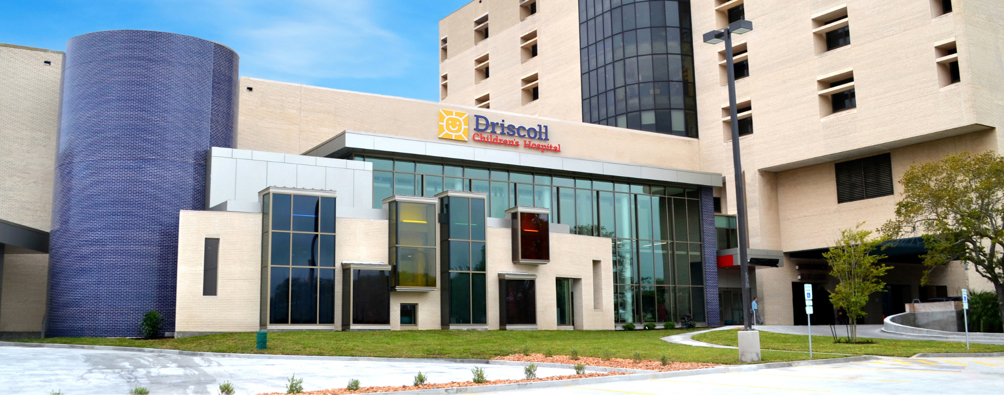 Exterior view of Driscoll Children’s Hospital with modern architectural design, including large glass windows and a visible hospital sign above the entrance.