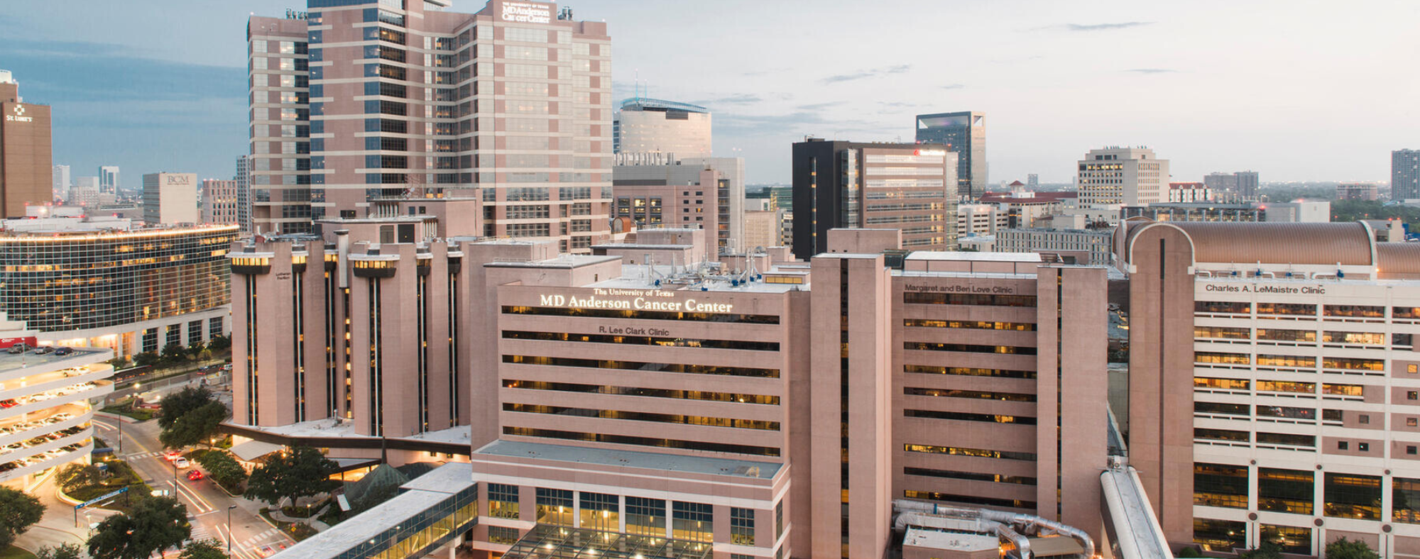 Aerial view of the Texas Medical Center with MD Anderson Cancer Center buildings and surrounding healthcare facilities at dusk.