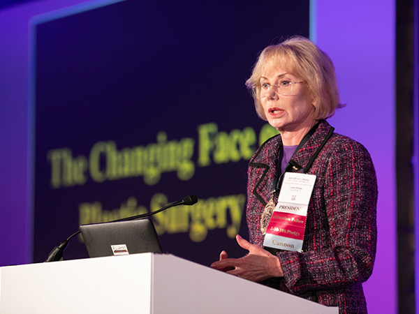 Plastic Surgeon Dr. Linda Phillips presenting at the American Association of Plastic Surgeons on "The changing face of plastic surgery" at podium, close up