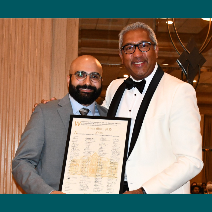 Two individuals in formal attire holding a framed certificate at an indoor event, posing together in front of a decorative interior setting.