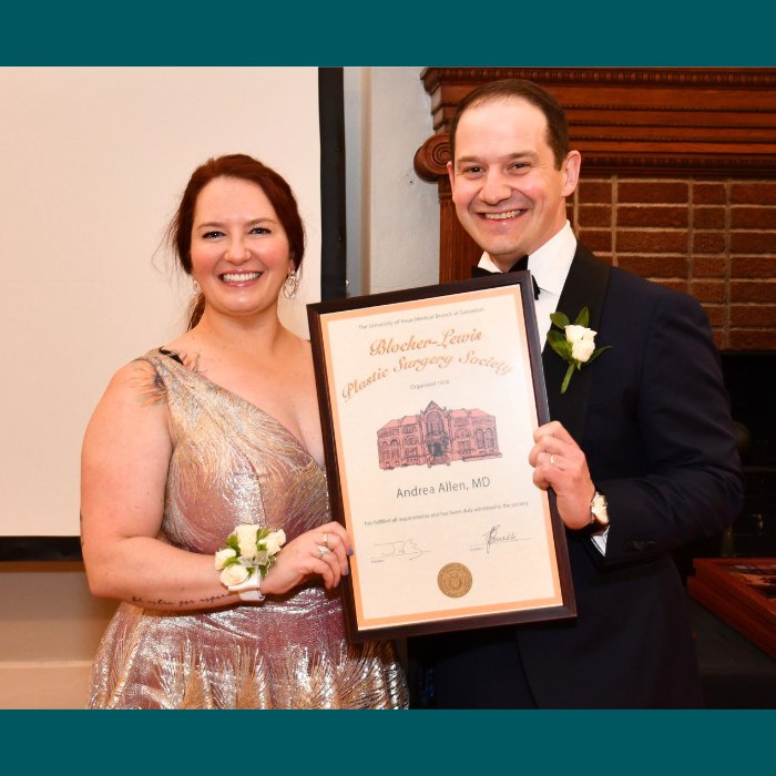 Two individuals in formal attire holding a framed certificate labeled “Blocher-Lewis Plastic Surgery Society” during an indoor ceremony.