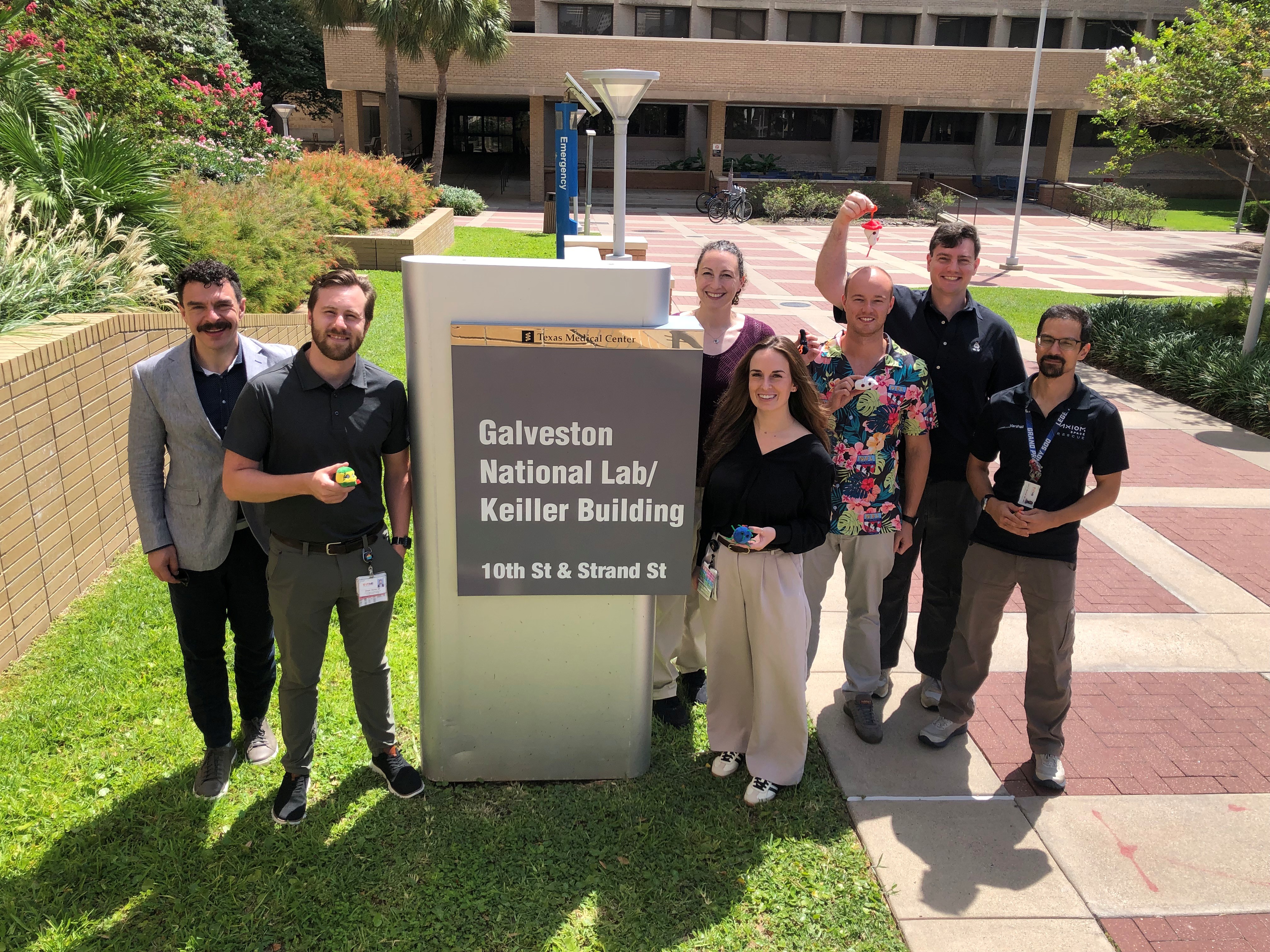 Aerospace Medicine Residents Photo shows seven young physicians who participate in the UTMB Aerospace Medicine Program standing in front of the sign for the Galveston National Lab