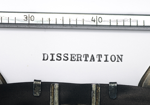 Typed word “DISSERTATION” on paper beneath a ruler.