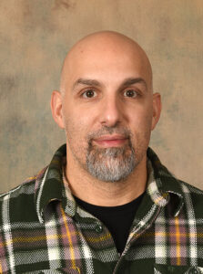man in a checkered shirt in a studio setting