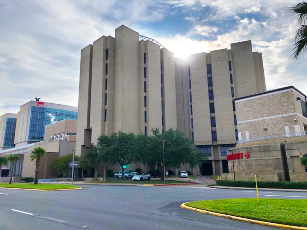 Exterior of TDCJ Hospital Galveston with emergency entrance and surrounding hospital buildings.