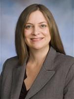 Professional headshot of Dr. Stephanie Zepeda wearing a gray suit jacket over a light top against a blue‑gray gradient background.
