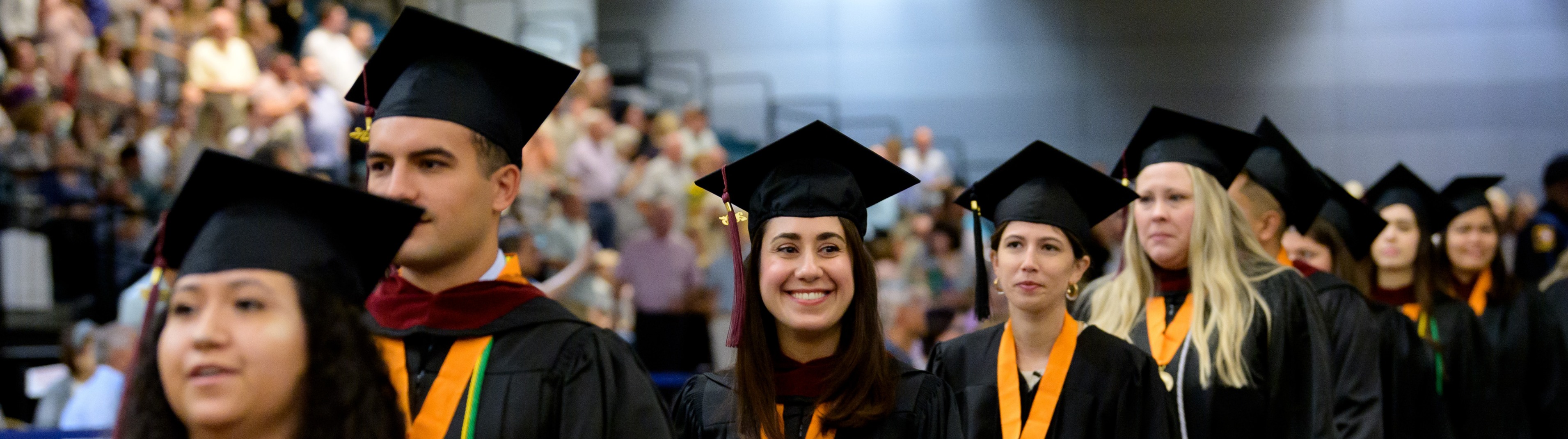 Graduate walking and smiling to family and friends in the stands