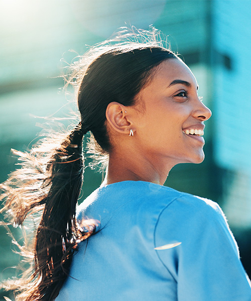 BSRT A healthcare professional in blue scrubs smiles while standing outside a modern medical building.