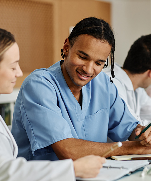 Entry-level MSRT students Respiratory therapy students in scrubs study together around a classroom table.