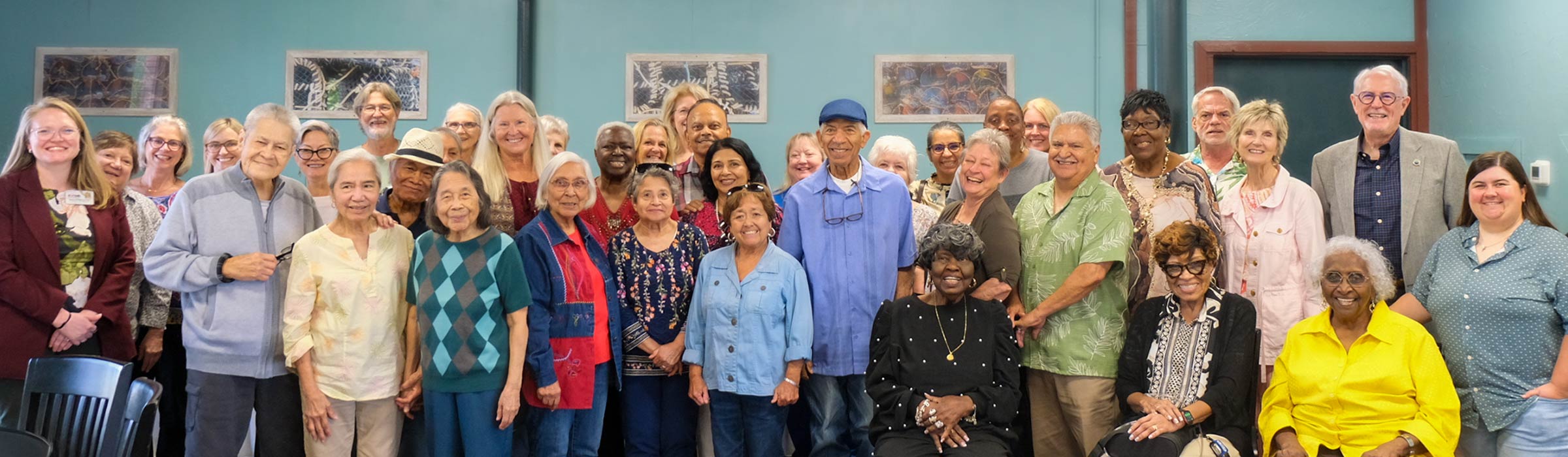 large diverse group of older adults with staff and faculty from SCOA, smiling in a restaurant settings