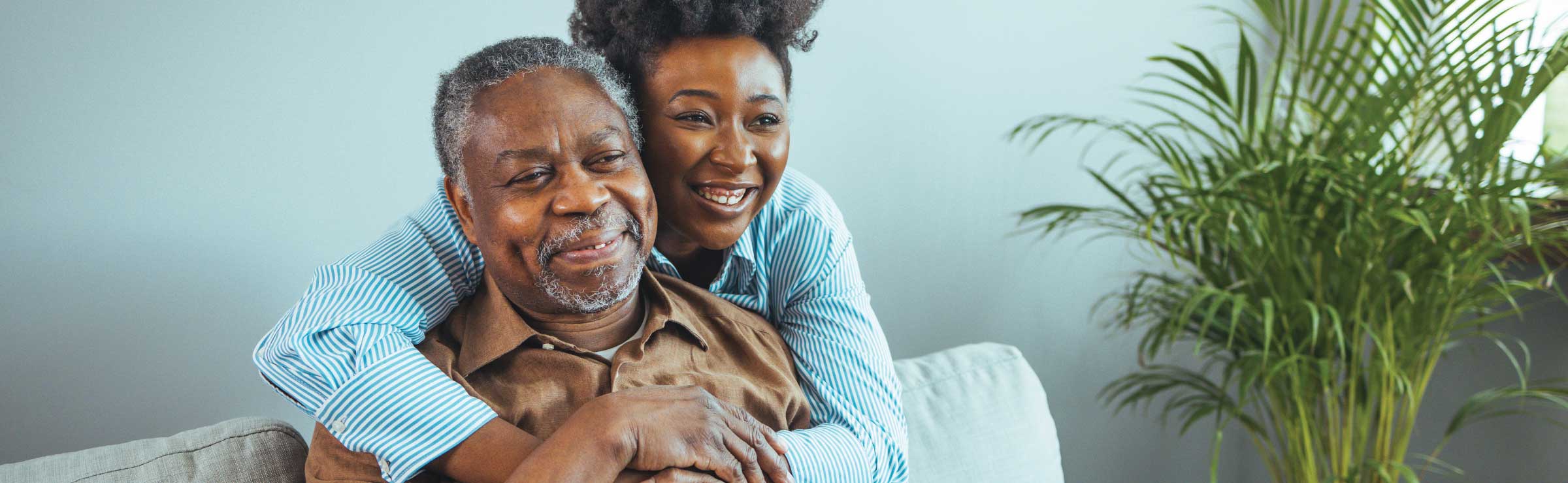 older adult man of color embraced by a younger woman of color in a home setting