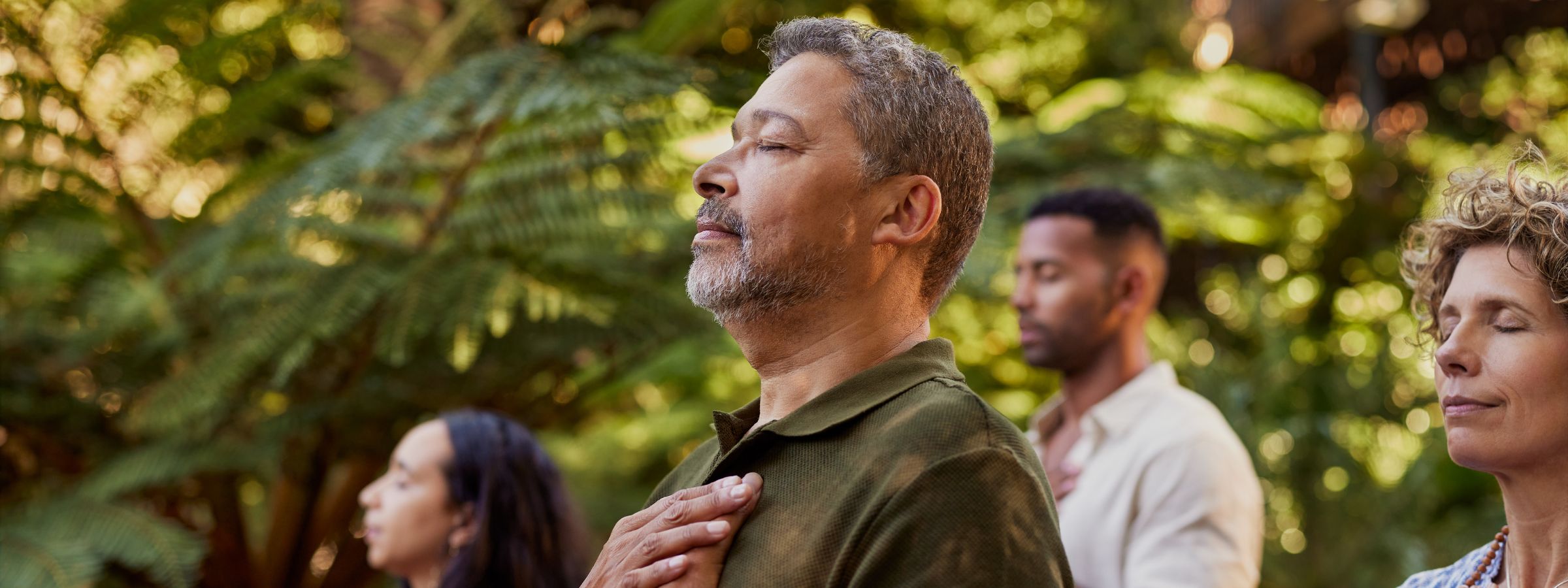 diverse group of older adults gathered outdoors with eyes closed, thoughtfully
