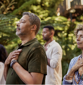 diverse group of adults together outdoors praying or meditating