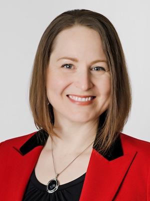 a woman wearing professional dress, smiling in a studio setting