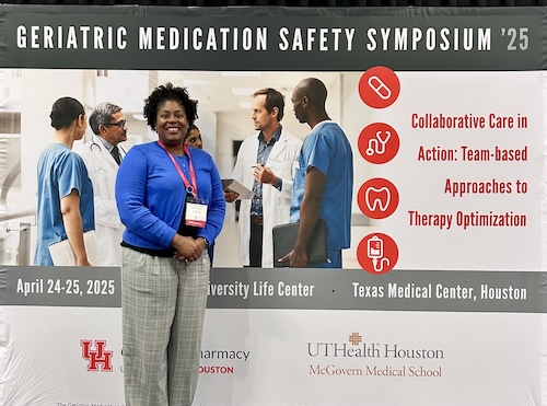 woman of color stands in front of signage for event